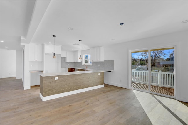 kitchen featuring a center island, tasteful backsplash, light hardwood / wood-style flooring, decorative light fixtures, and white cabinets