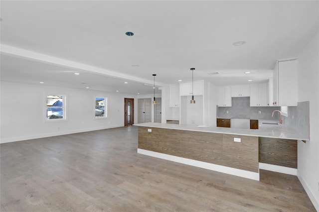 kitchen featuring white cabinetry, backsplash, pendant lighting, light hardwood / wood-style floors, and a kitchen island