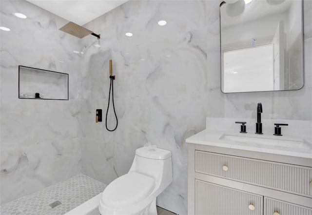 bathroom featuring vanity, toilet, tile walls, and a tile shower