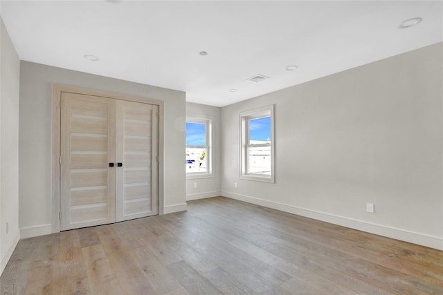 unfurnished bedroom with light wood-type flooring and a closet