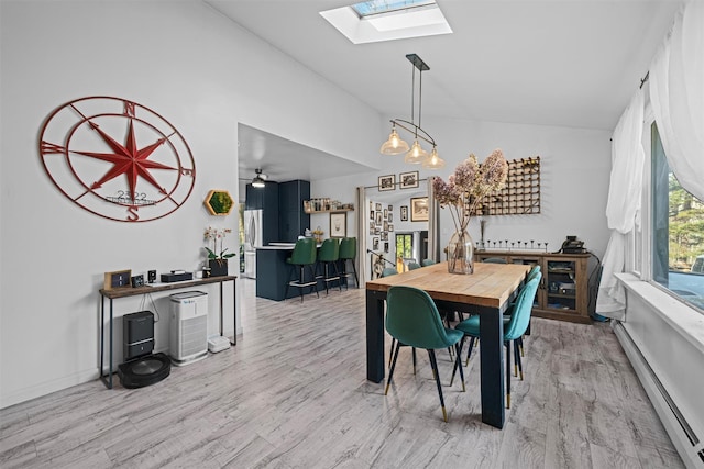 dining area with a baseboard heating unit, vaulted ceiling with skylight, and light wood-type flooring