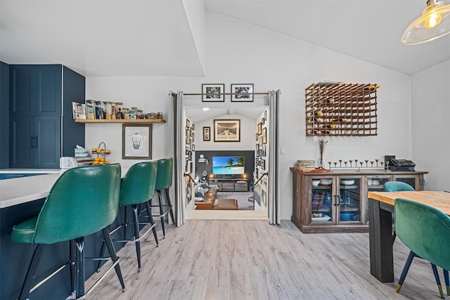 bar with lofted ceiling, light hardwood / wood-style flooring, and blue cabinetry