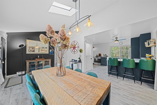 dining area with a skylight, light hardwood / wood-style floors, ceiling fan, and baseboard heating