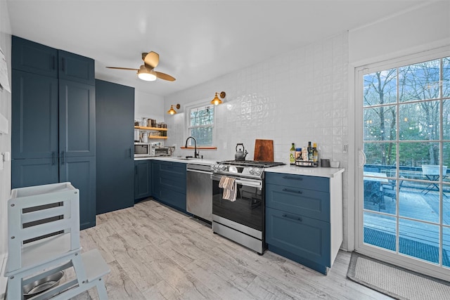 kitchen featuring sink, ceiling fan, stainless steel appliances, blue cabinetry, and light hardwood / wood-style flooring