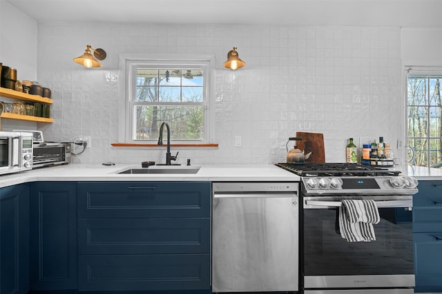 kitchen featuring blue cabinets, sink, backsplash, and appliances with stainless steel finishes