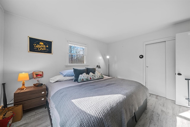 bedroom with light hardwood / wood-style floors and a closet