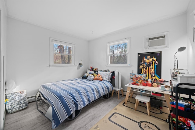 bedroom with a baseboard heating unit, a wall mounted air conditioner, and light wood-type flooring