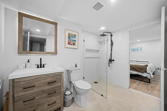 bathroom with vanity, a tile shower, and toilet