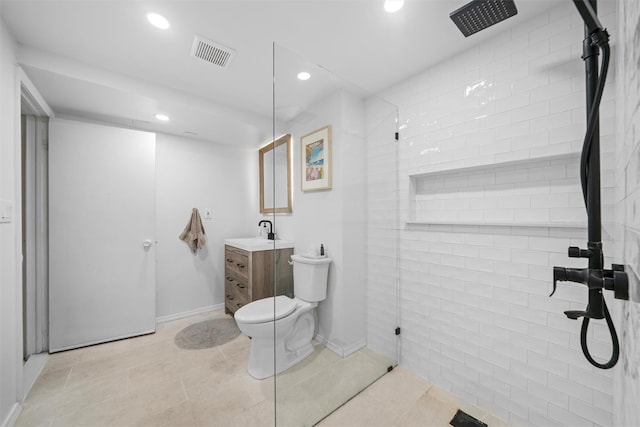 bathroom with tile patterned floors, vanity, toilet, and a tile shower