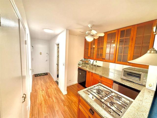 kitchen with light stone countertops, ceiling fan, light hardwood / wood-style flooring, black dishwasher, and stainless steel gas stovetop