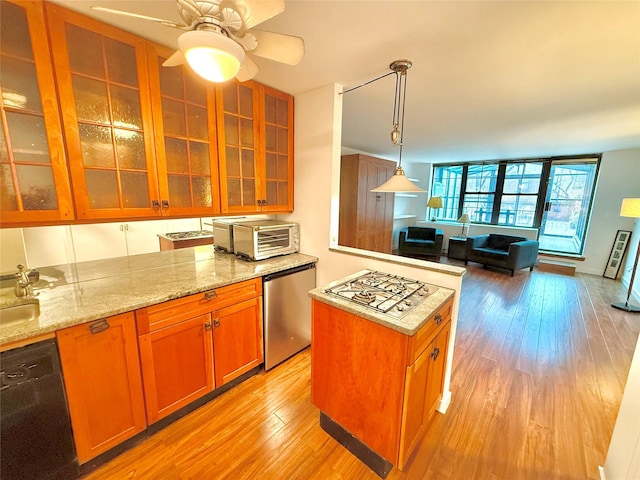 kitchen featuring hanging light fixtures, light hardwood / wood-style flooring, ceiling fan, light stone countertops, and appliances with stainless steel finishes