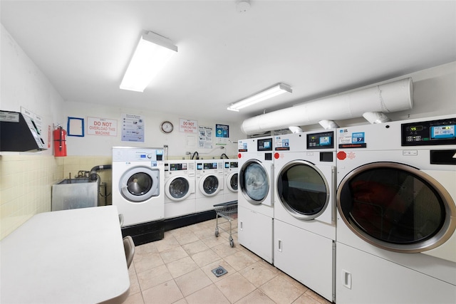 laundry room with separate washer and dryer, light tile patterned floors, and tile walls