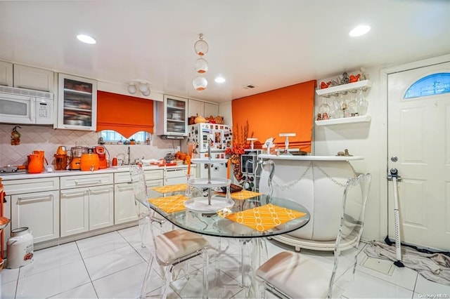 kitchen with white cabinets, backsplash, a breakfast bar area, and sink