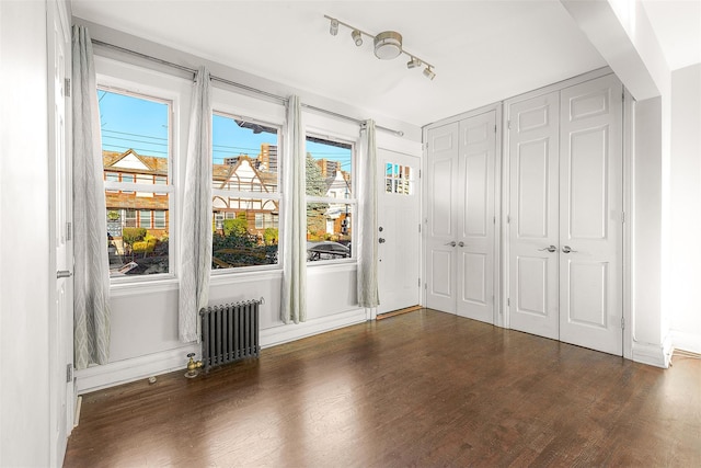 unfurnished bedroom with dark hardwood / wood-style flooring and radiator