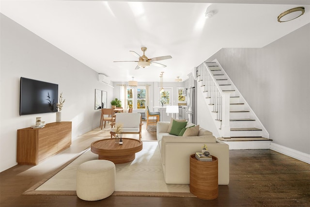 living room with hardwood / wood-style flooring, ceiling fan, and an AC wall unit