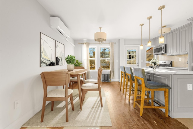 dining area with light hardwood / wood-style floors, sink, radiator, and a wall mounted AC