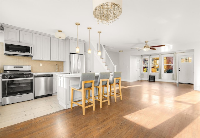 kitchen with light hardwood / wood-style flooring, a center island, decorative light fixtures, and appliances with stainless steel finishes