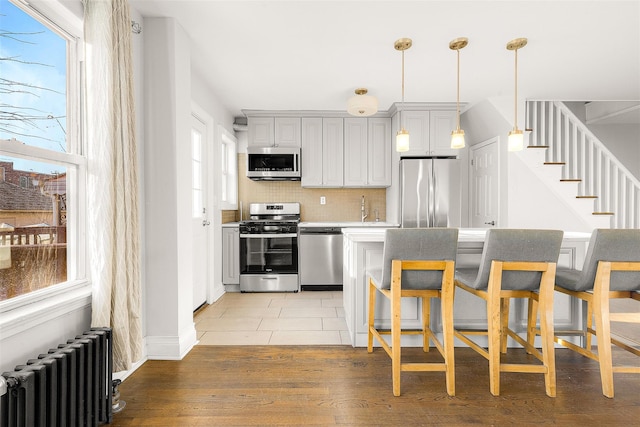 kitchen with radiator, a healthy amount of sunlight, stainless steel appliances, and light hardwood / wood-style floors