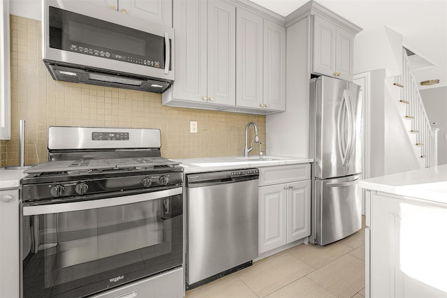 kitchen with white cabinets, light tile patterned floors, backsplash, and appliances with stainless steel finishes