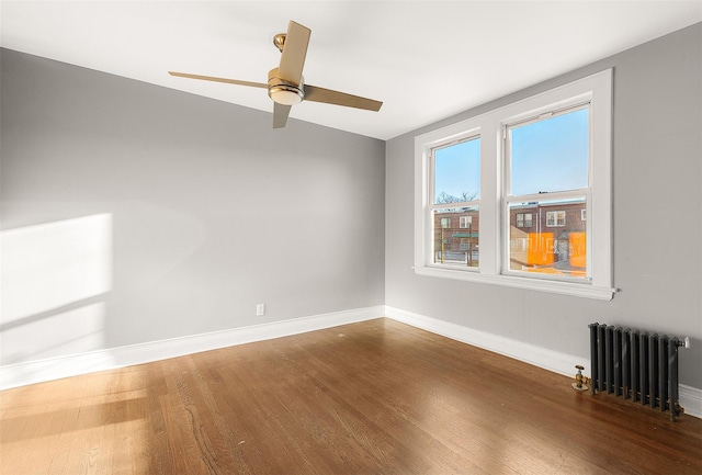 empty room featuring ceiling fan, wood-type flooring, and radiator