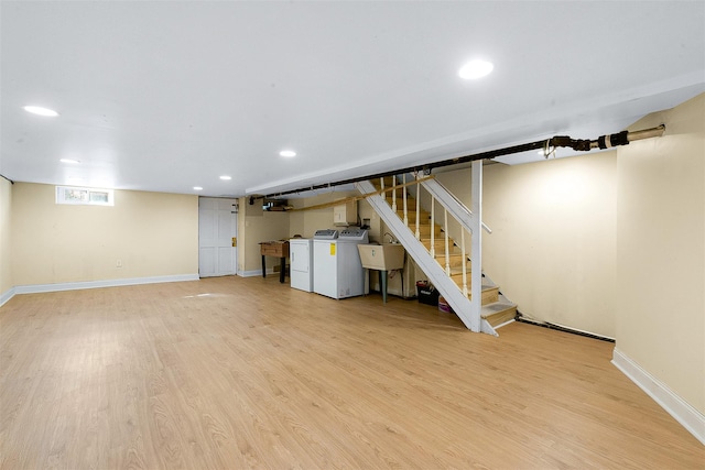 basement with light hardwood / wood-style floors, sink, and washer and dryer