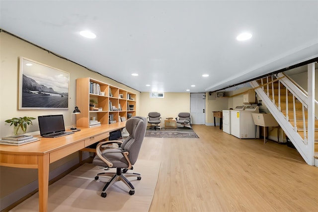 office featuring built in desk, light hardwood / wood-style floors, and washer and dryer