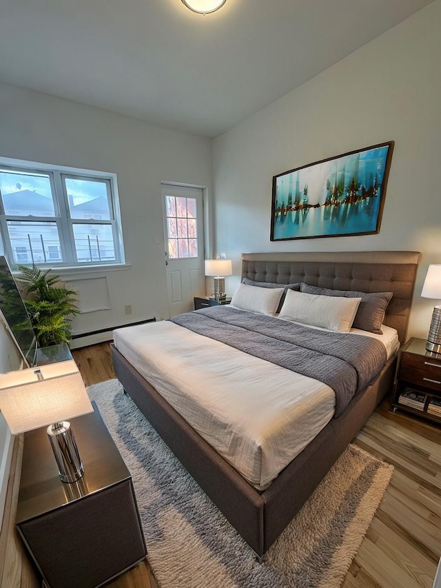 bedroom with baseboard heating and hardwood / wood-style floors