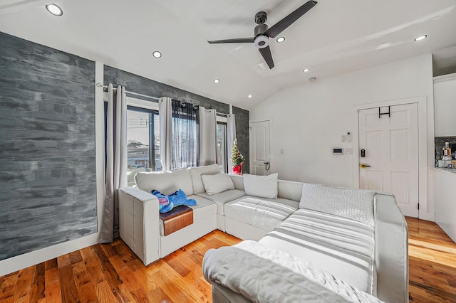 living room featuring ceiling fan, light wood-type flooring, and vaulted ceiling