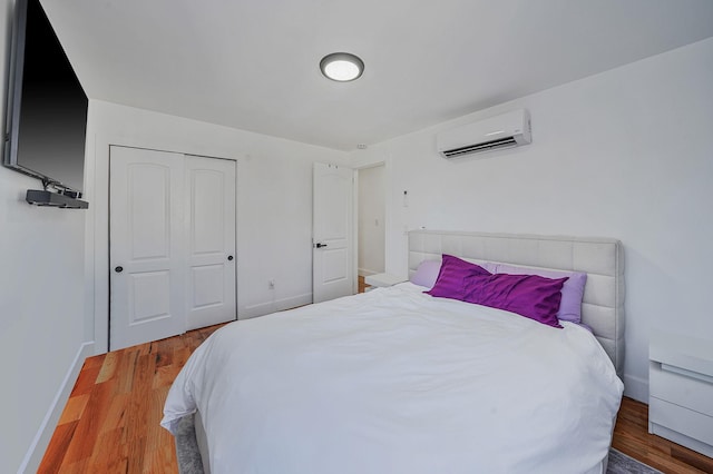 bedroom with a wall unit AC, a closet, and hardwood / wood-style flooring