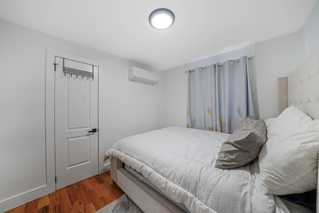 bedroom featuring a wall unit AC and dark wood-type flooring