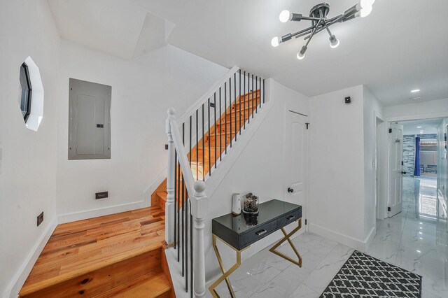 stairway with electric panel and an inviting chandelier