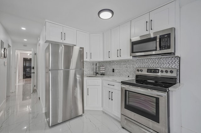 kitchen featuring tasteful backsplash, white cabinetry, stainless steel appliances, and light stone counters