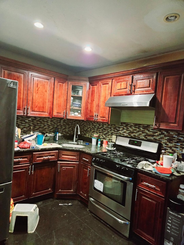 kitchen with dark tile patterned flooring, black fridge, sink, stainless steel gas range, and tasteful backsplash