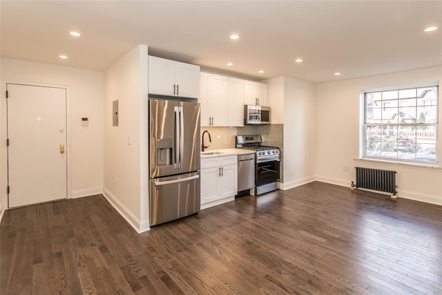 kitchen featuring white cabinetry, appliances with stainless steel finishes, radiator, and sink