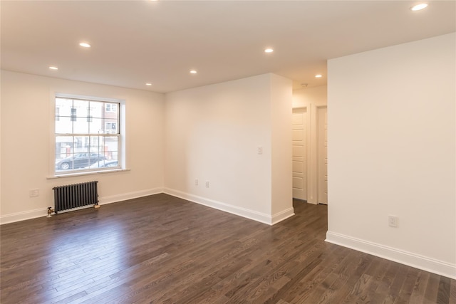 spare room featuring radiator and dark hardwood / wood-style floors