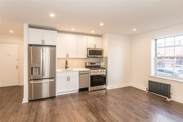 kitchen featuring dark wood-type flooring, white cabinets, appliances with stainless steel finishes, and radiator heating unit