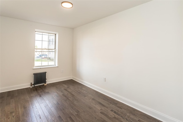 spare room featuring dark wood-type flooring and radiator