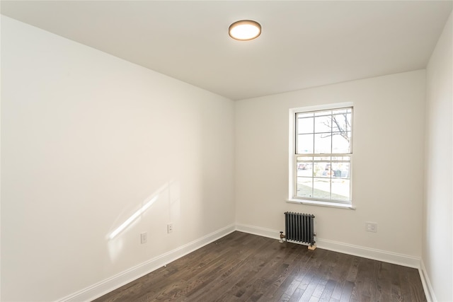 spare room featuring radiator and dark wood-type flooring