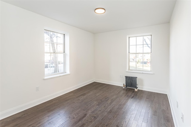 unfurnished room featuring dark wood-type flooring, radiator heating unit, and plenty of natural light