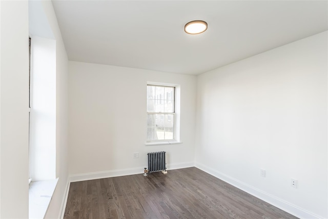 empty room featuring radiator heating unit and dark hardwood / wood-style flooring