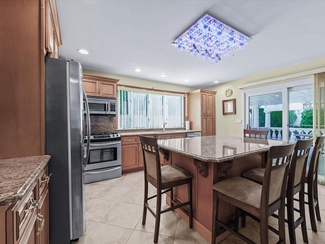 kitchen featuring a breakfast bar, a healthy amount of sunlight, a kitchen island, and stainless steel appliances