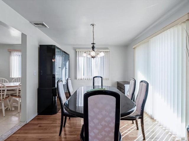 dining area featuring hardwood / wood-style floors, a healthy amount of sunlight, and a notable chandelier