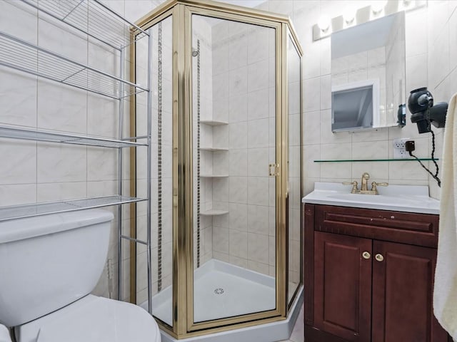 bathroom with tasteful backsplash, toilet, a shower with door, vanity, and tile walls