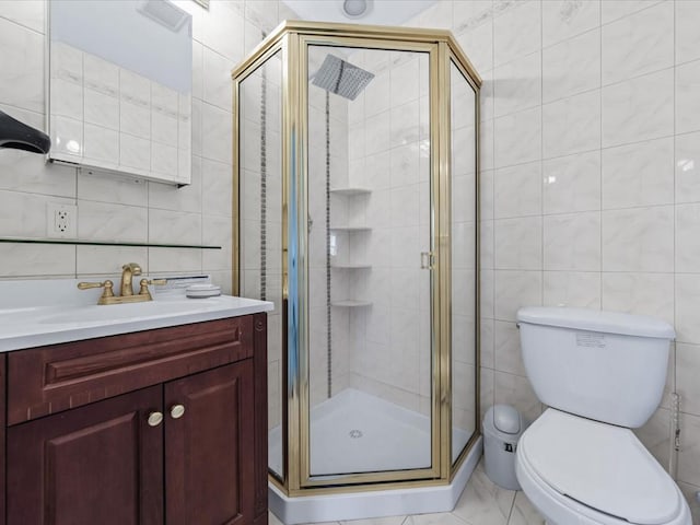 bathroom featuring vanity, toilet, tile walls, and a shower with shower door