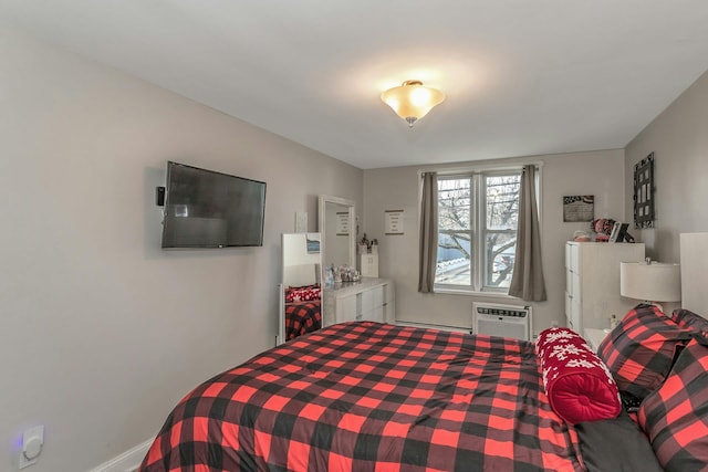 bedroom featuring a wall unit AC and a baseboard heating unit