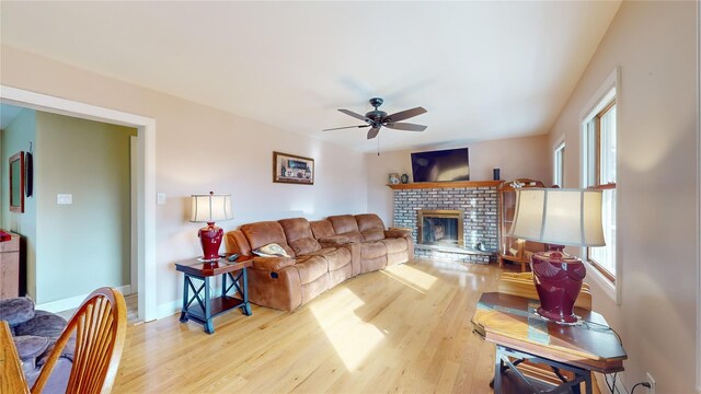 living room featuring ceiling fan, light hardwood / wood-style floors, and a fireplace