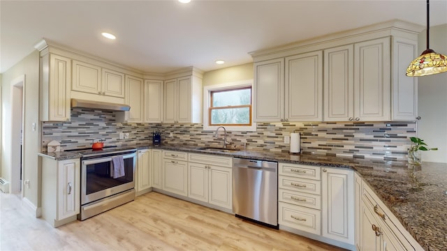 kitchen with sink, cream cabinets, light hardwood / wood-style floors, pendant lighting, and appliances with stainless steel finishes