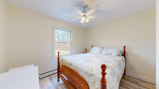 bedroom featuring ceiling fan, light wood-type flooring, and a baseboard heating unit