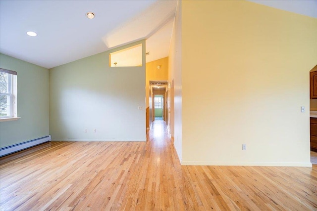 unfurnished room featuring light hardwood / wood-style floors, a baseboard heating unit, and vaulted ceiling