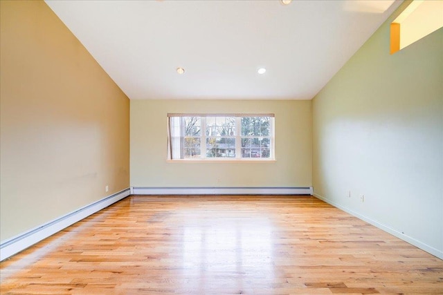 unfurnished room with vaulted ceiling, baseboard heating, and light hardwood / wood-style flooring